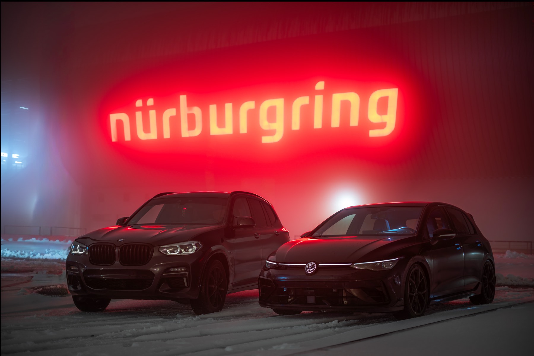 Zwei Fahrzeuge vor dem leuchtenden Nürburgring Schriftzug